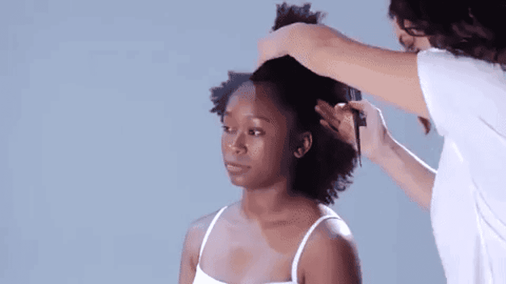 Gif of Freddie from BuzzFeed Ladylike getting her curly hair separated into three buns 
