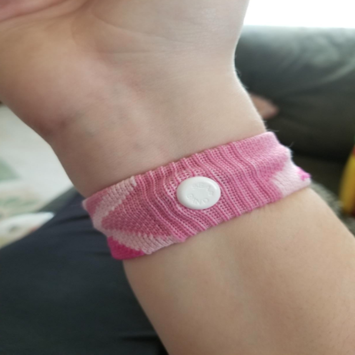 Reviewer wearing the bracelet; it's pink knit with a single plastic piece that puts pressure on the wrist