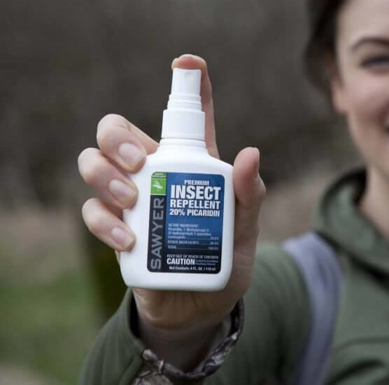 A hand holding a spray bottle of the repellent