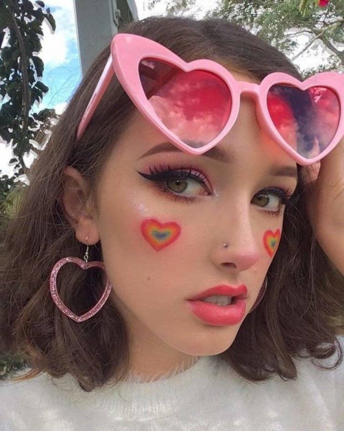 model wears pink heart shaped sunglasses with pink lenses 