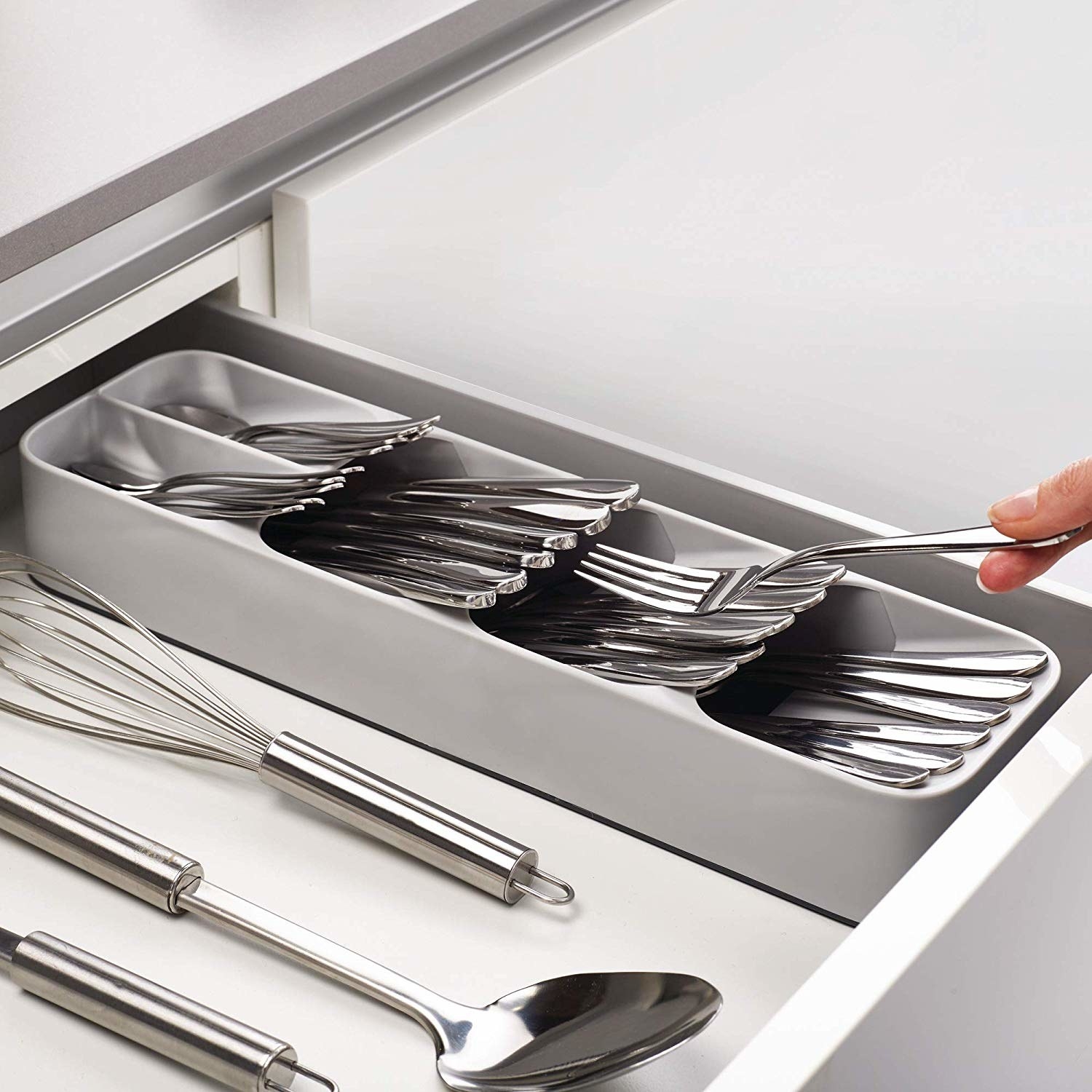 The tray, taking up just a fraction of the drawer, with three full sections filled with silverware and one section divided in half, but also packed with silverware