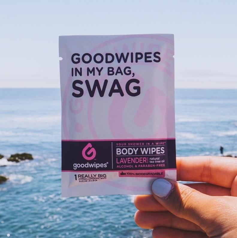 Hand holding purple wipe packet with the words, &quot;Goodwipes in my bag, swag&quot; 