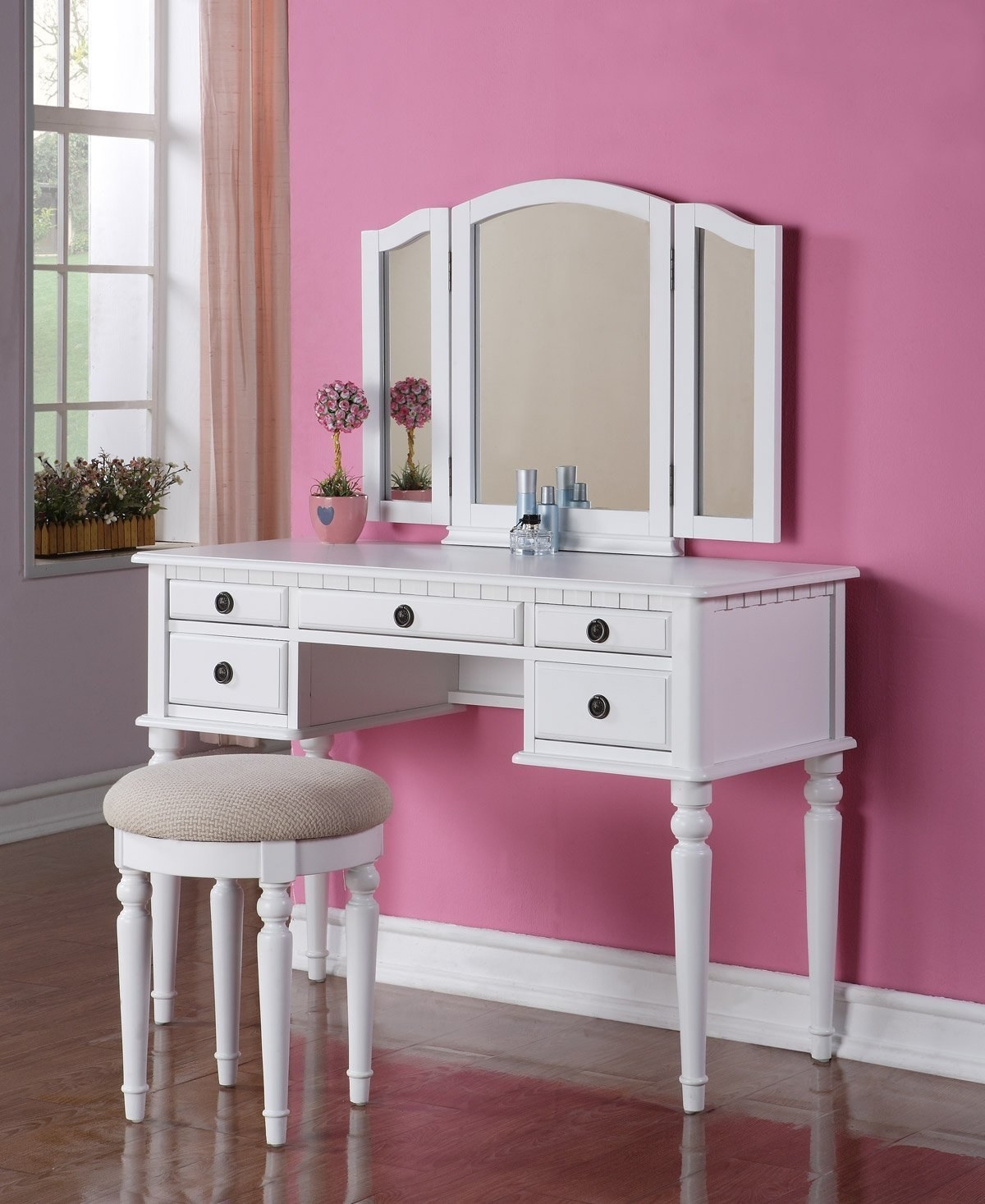 The vanity with five drawers in the front and a three-part mirror in white with a small stool with a padded fabric top