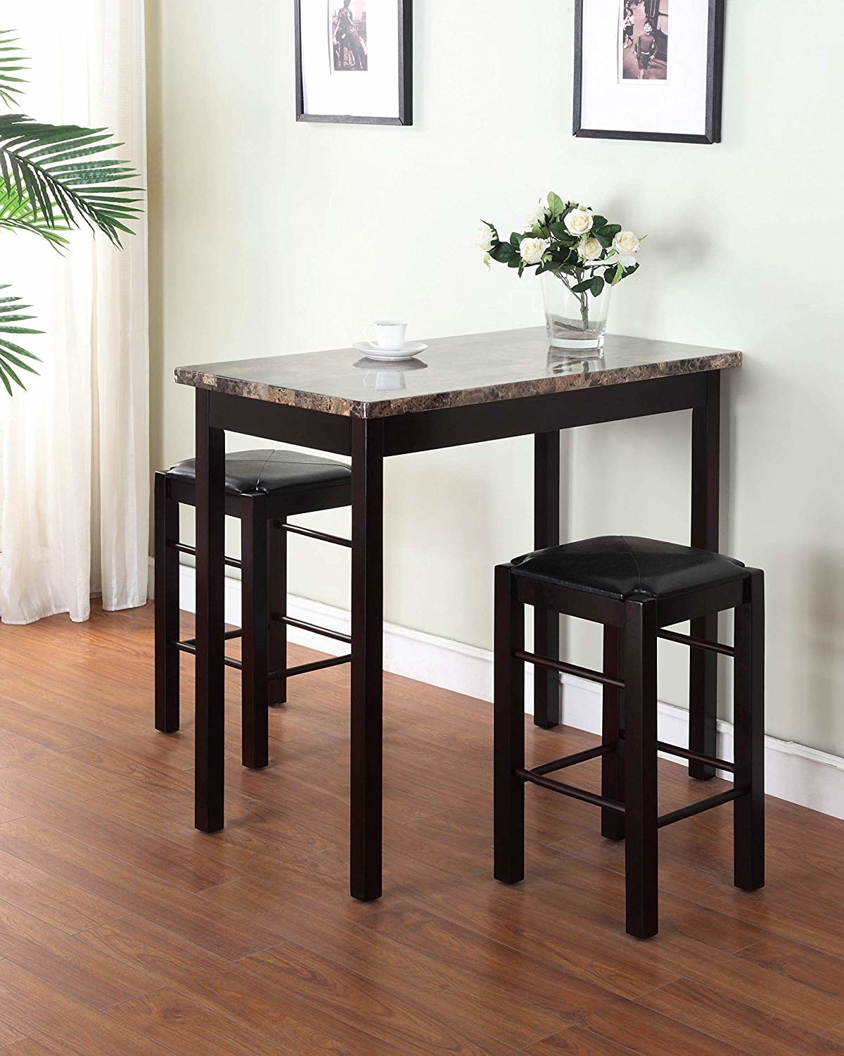 A tall table in brown with a marble-like top and two stools on either side of it, also in brown