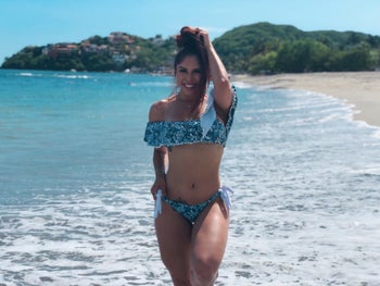 reviewer wearing the off-the-shoulder bikini in blue print