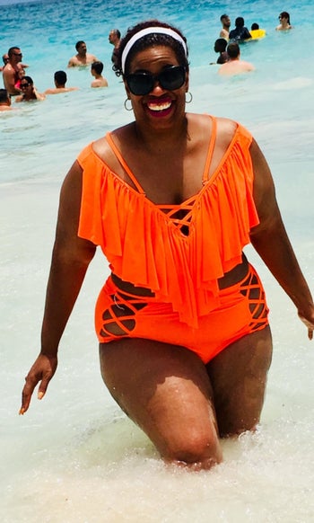 reviewer wearing the high-waisted bikini with criss-cross straps on the side of the bottoms and middle of the chest in bright orange