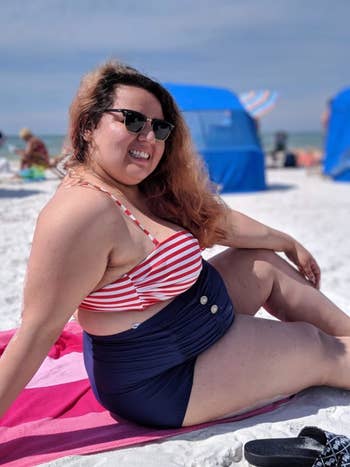 reviewer wearing bathing suit sitting on a towel at the beach