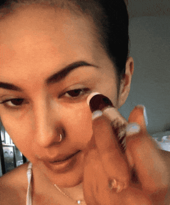 Gif of the same BuzzFeeder applying the concealer on the under-eye area