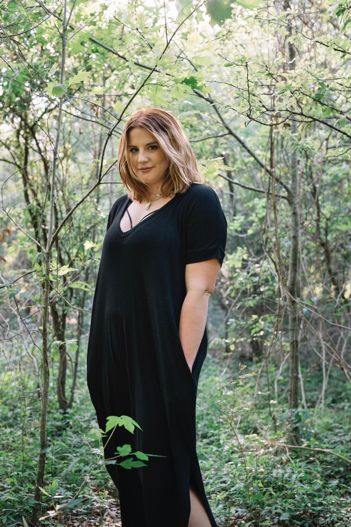 reviewer wears short sleeve black maxi dress and puts hands in pockets 