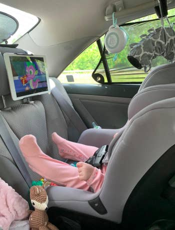 Reviewer's tablet hanging in front of a child on the headrest in their car