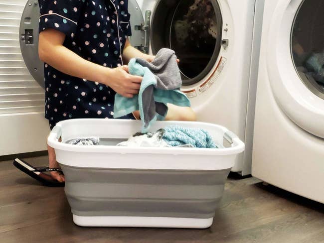 model unloading towels from a hamper into a washing machine