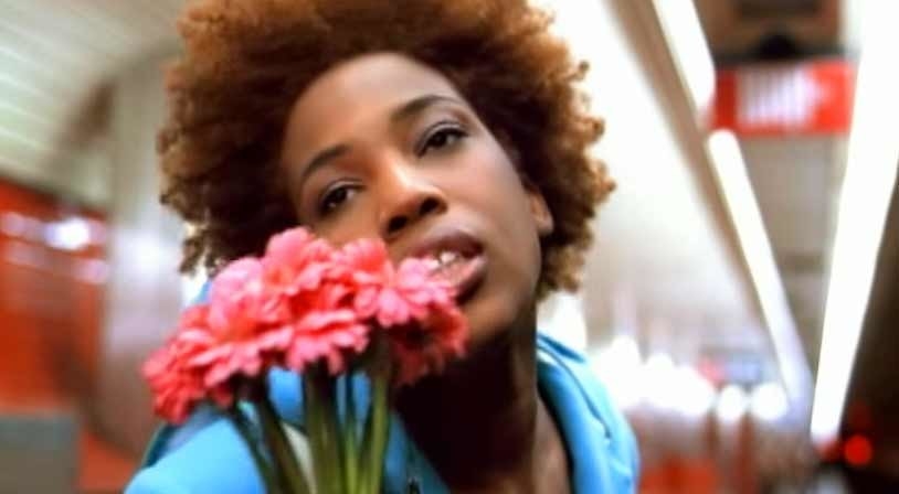 Macy Gray holding up flowers in a subway station