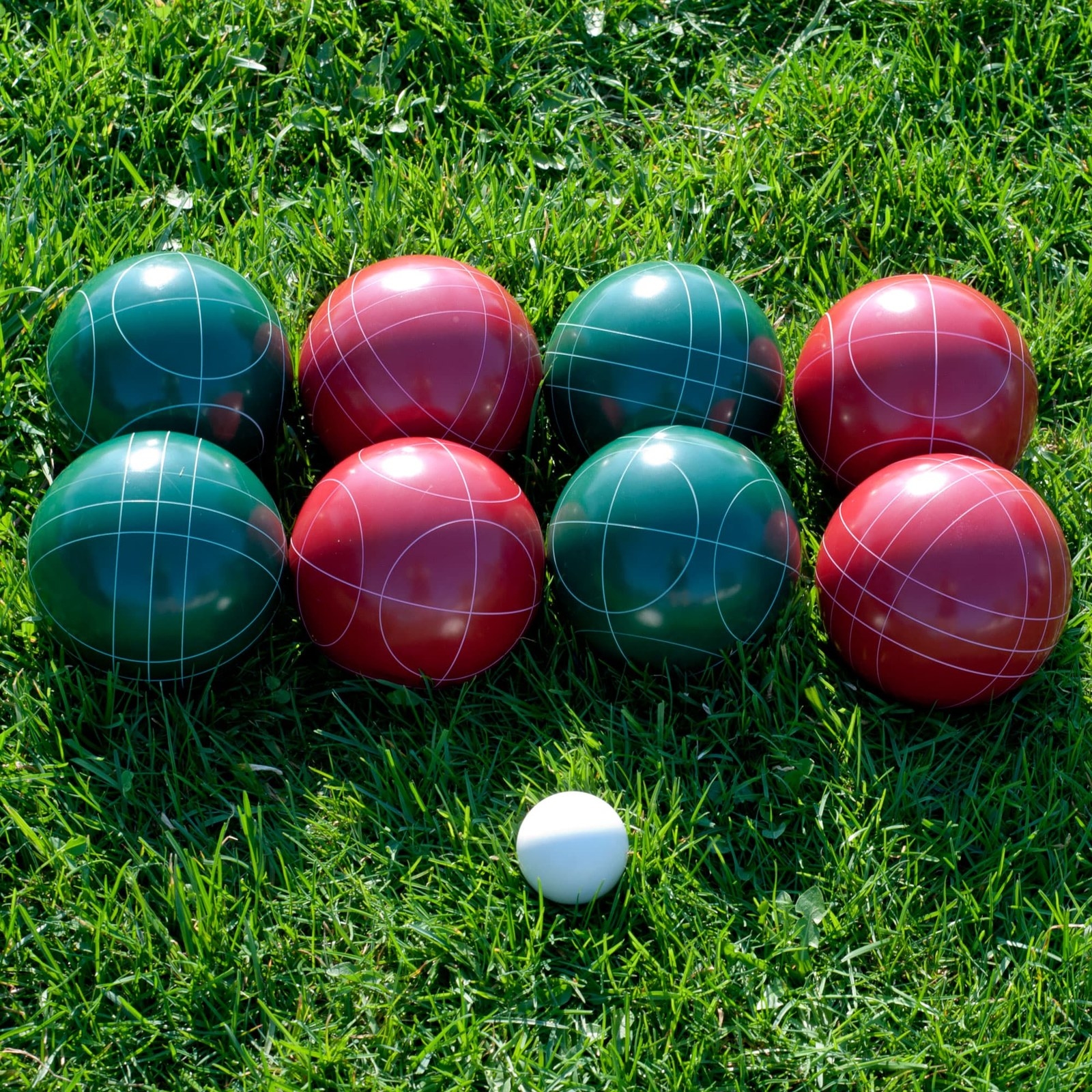 bocce set in a yard with green and red balls