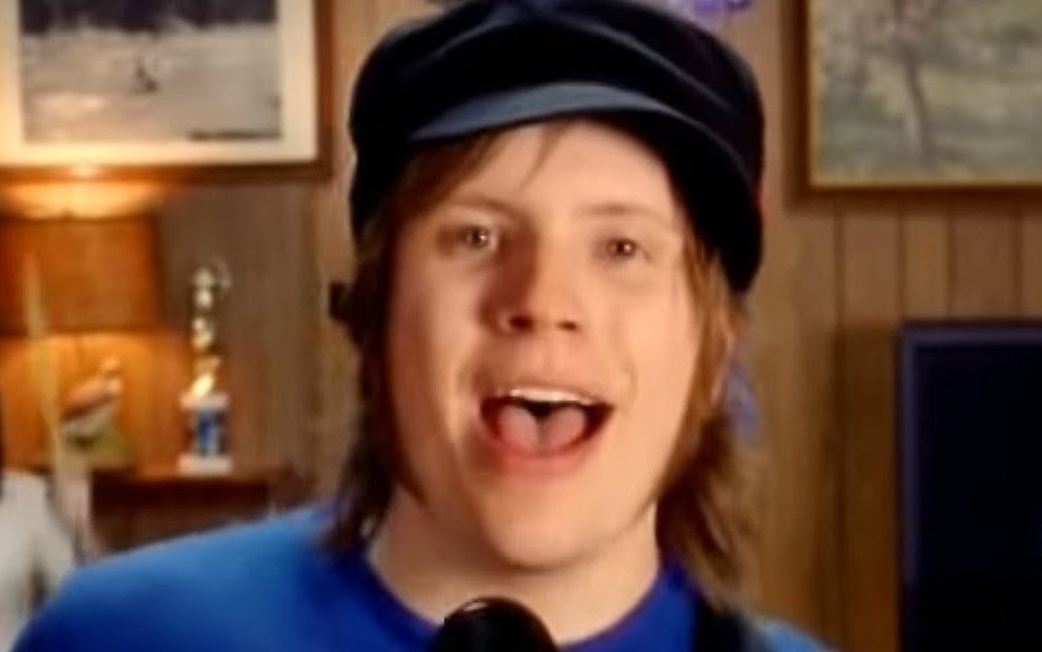 Patrick Stump wears a newsboy cap and T-shirt to sing into a mic
