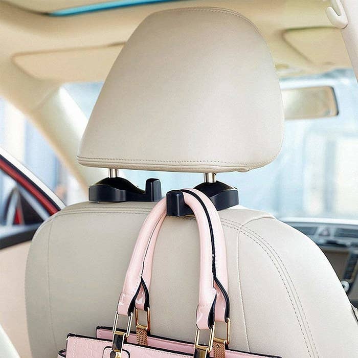 a pink bag being hung from the hook behind the front seat of a car