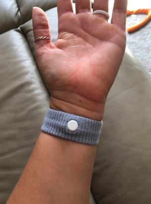 A reviewer wearing the band on their wrist with the pressure point button in the center 