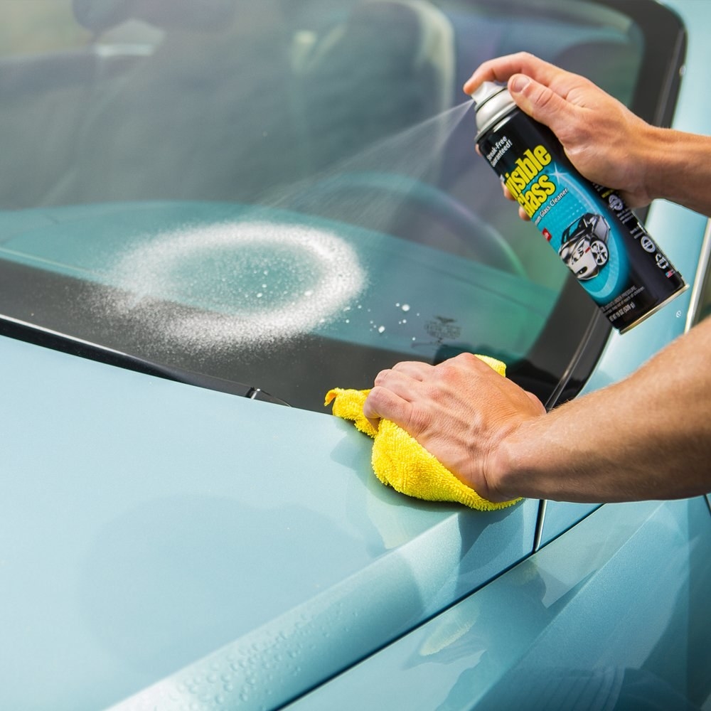 a model using the glass cleaner on a car windshield
