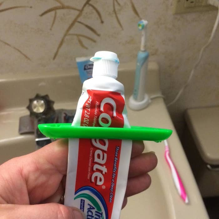 Reviewer a tube of toothpaste with a green dispenser on it, showing how it pushes all the toothpaste out