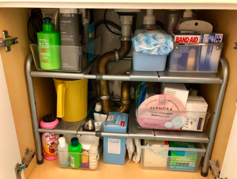 reviewer pic of inside a bathroom vanity cabinet with a lot of organized items in a small space thanks to the adjustable organizer