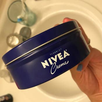 Reviewer holding tub of Nivea Creme