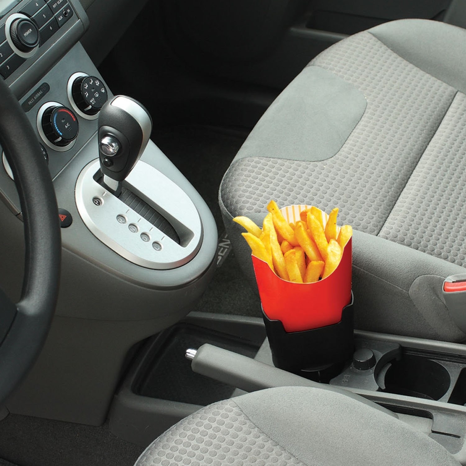 A packet of fries being held in the holder, which is placed inside a car cupholder