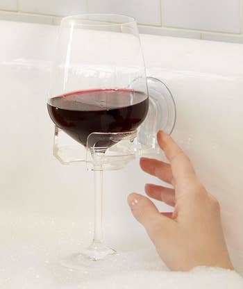Glass of wine attached to cup holder in bath tub 