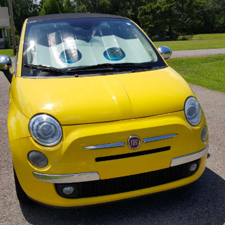 A reviewer's yellow Fiat with the eye window shade behind the windshield, giving the car a cartoonish appearance 