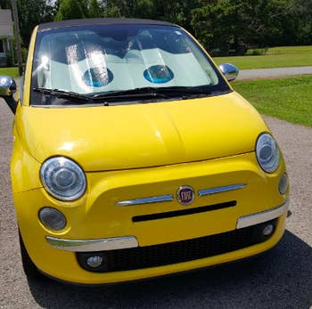 Reviewer photo of a yellow fiat with eyeball sunshade in the windshield 