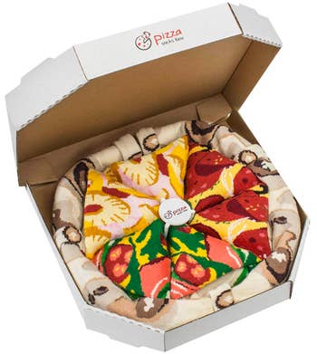 A classic pizza box filled with socks that look like crust, veggie slices, pepperoni slices, and pineapple slices