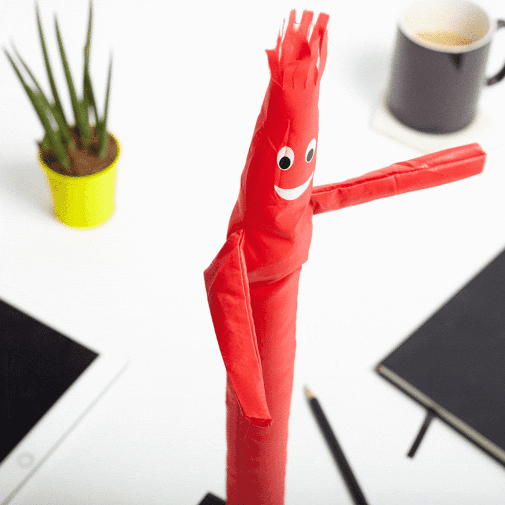 Gif of mini inflatable character jumping about on a desk when the air is turned on underneath it 