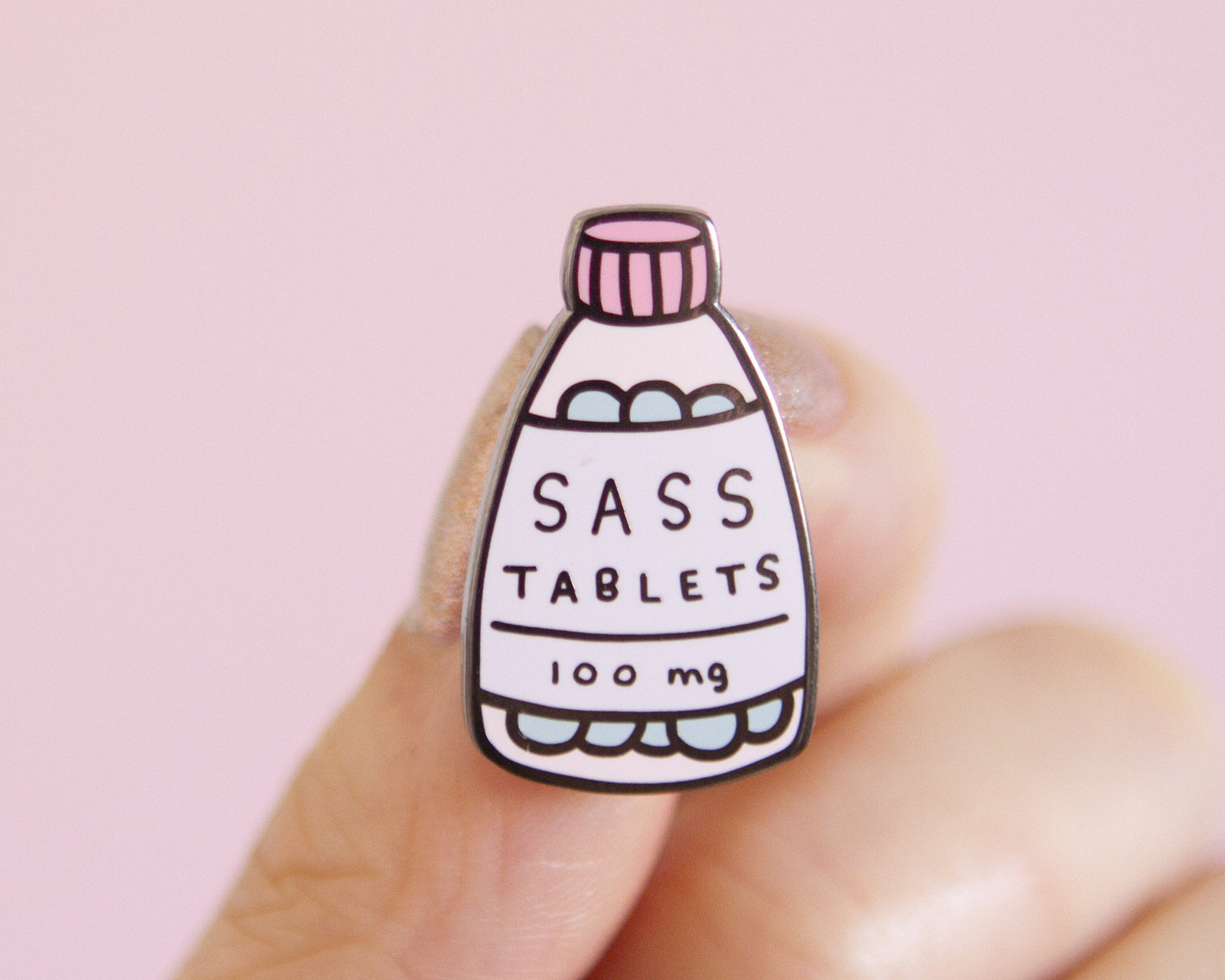 A small pink pin that looks like a bottle of pills. The pin says &quot;Sass Tablets&quot; 