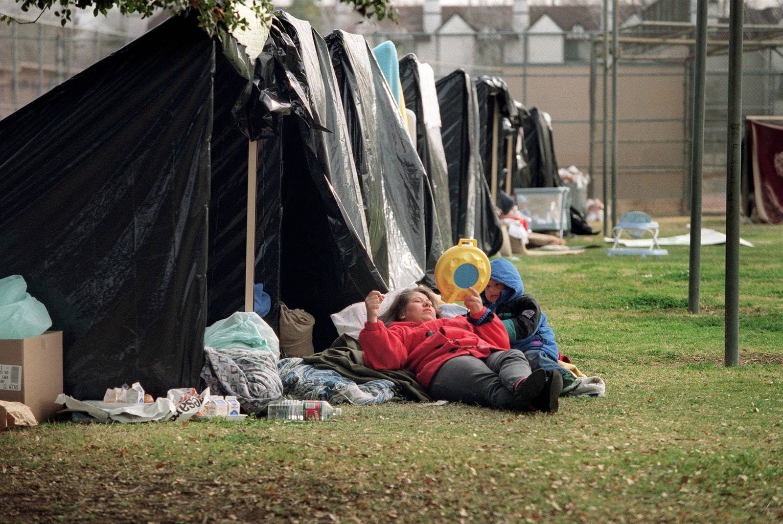 Mike Nelson / AFP / Getty Images A mother sews outside her tent as her son looks on in a camp installed by the National Guard on Jan. 22 in Canoga Park.