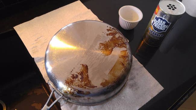 a pan that's half rusted and dirty and half shiny and clean with the cleaner next to it
