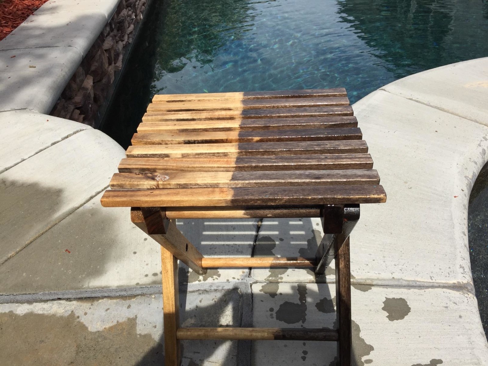 reviewer image of dark table with half of it cleaned by the pressure washer to show light wood underneath 