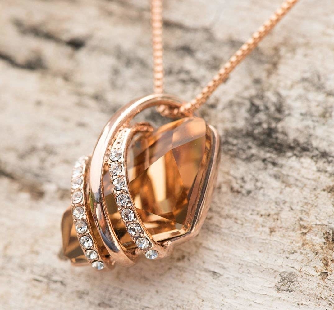 a rose gold necklace with crystals wrapped around a birthstone
