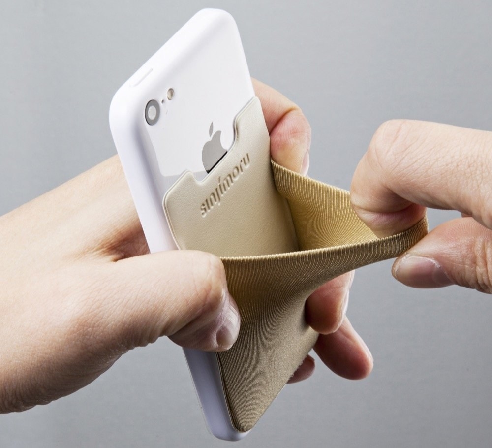 a hand opening the stick-on wallet, which is attached to the back of an iphone