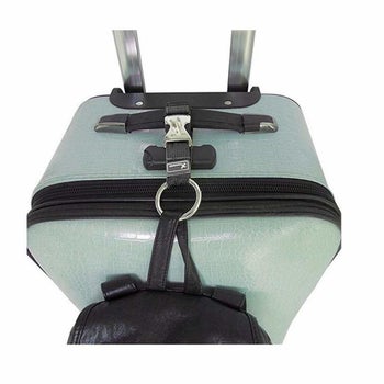 The black strap attaching a backpack to a suitcase