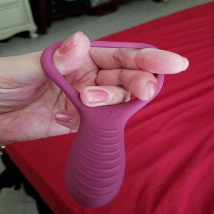 Hand stretches handle of same vibrating cock ring