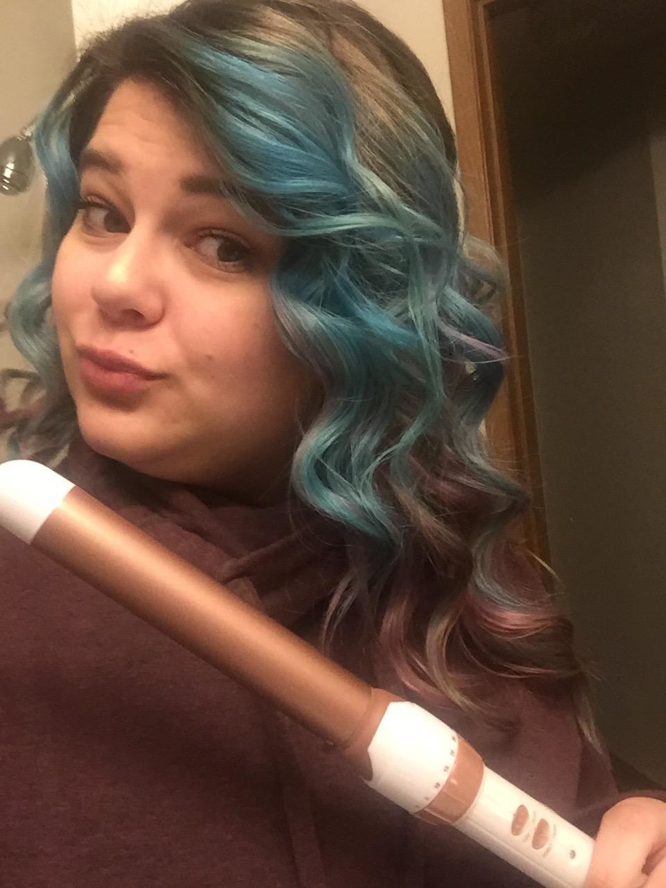 A reviewer with curls and holding the wand