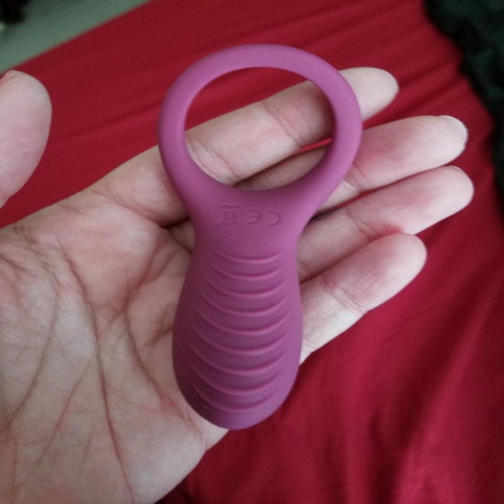 Hand holds pink vibrating cock ring