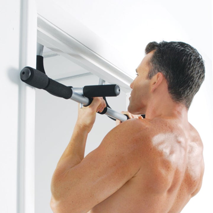 Model doing a pull-up with the silver and black bar attached between a door frame