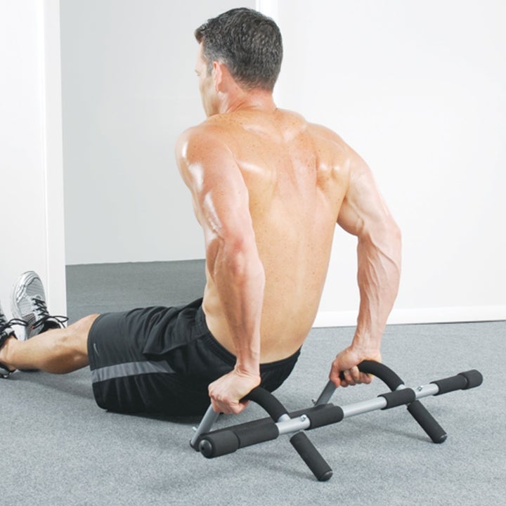 The same model now using the bar on the floor, doing tricep dips