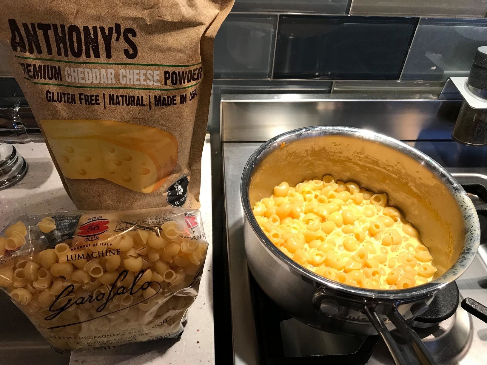 bowl of really cheesy looking mac and cheese next to the bag of powdered cheese 