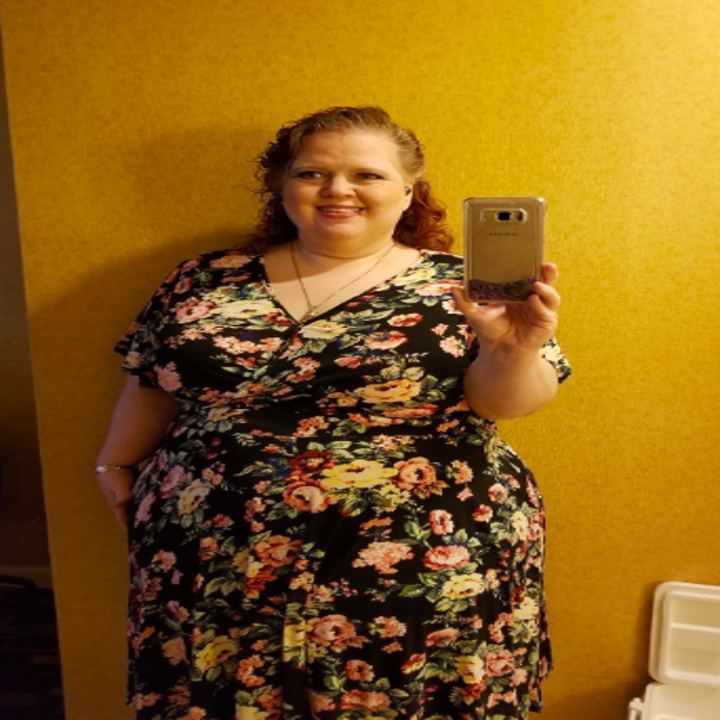 A reviewer wearing the short-sleeve dress in black and floral print