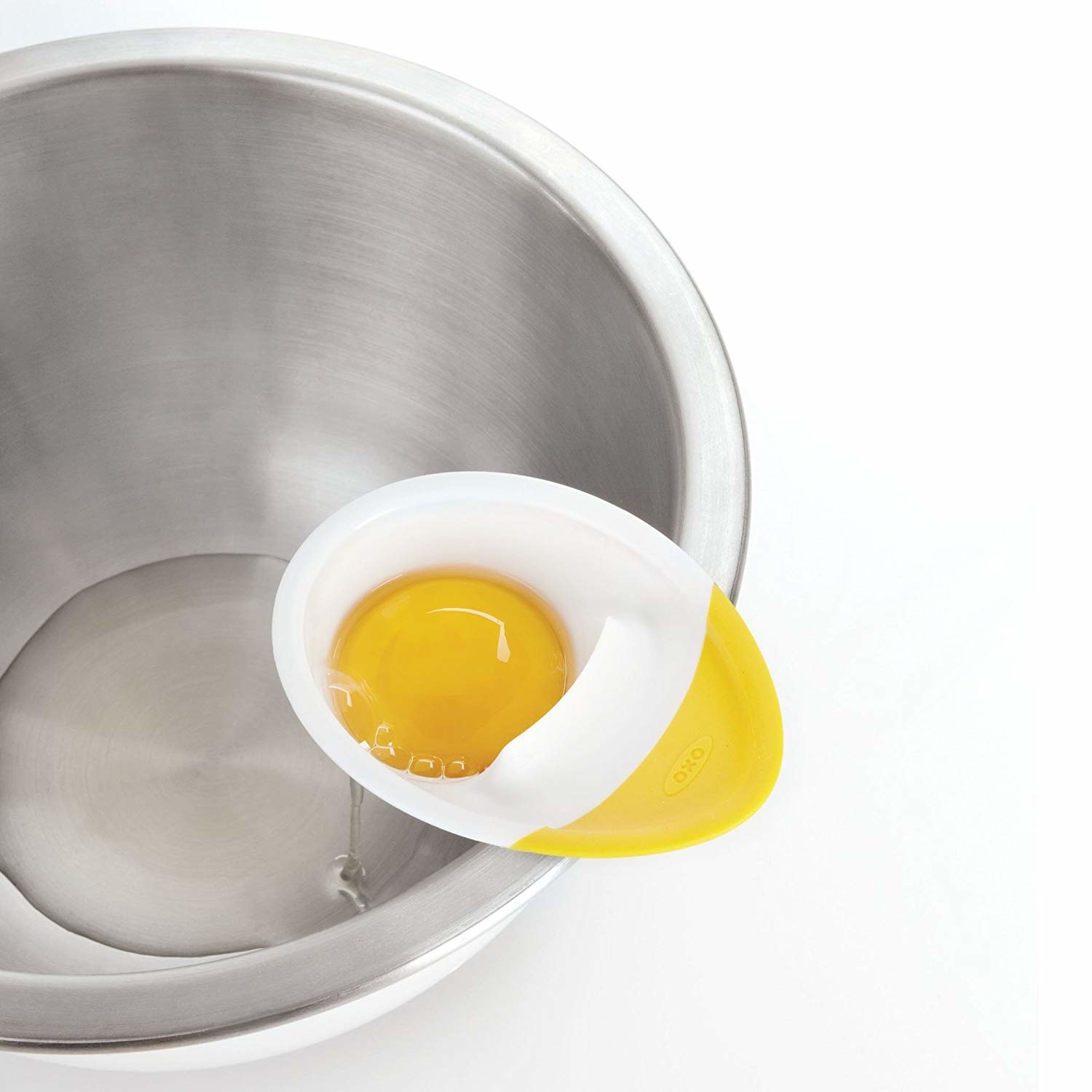 egg separator attached to side of bowl with the white dripping into the bowl