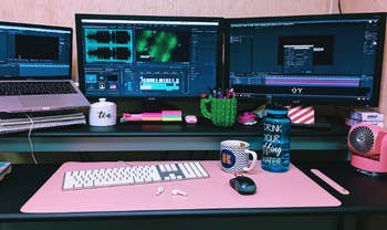 A pink version sitting on a desk with a keyboard, wireless mouse and mug.