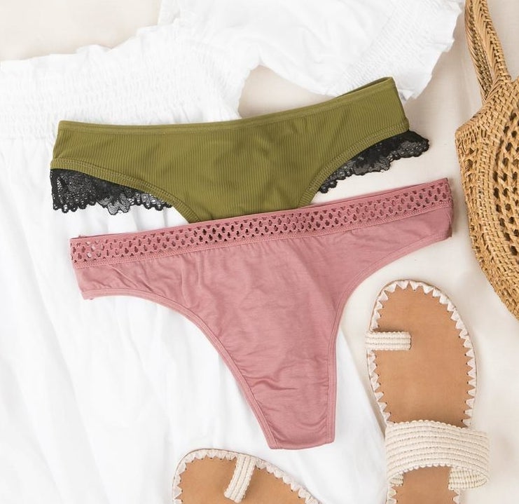 a pair of pink underwear and a pair of green underwear with black lace trim laid out on white fabric
