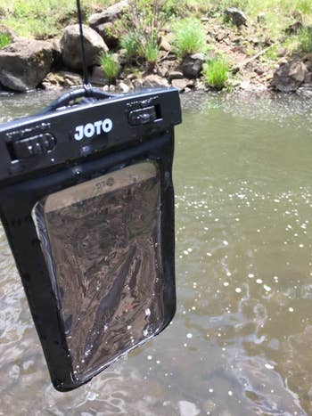 reviewer's phone in the waterproof pouch held over a river
