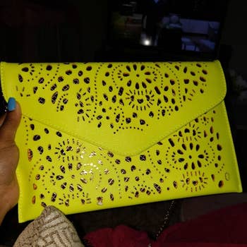 reviewer holding the purse in bright green with gold lining 
