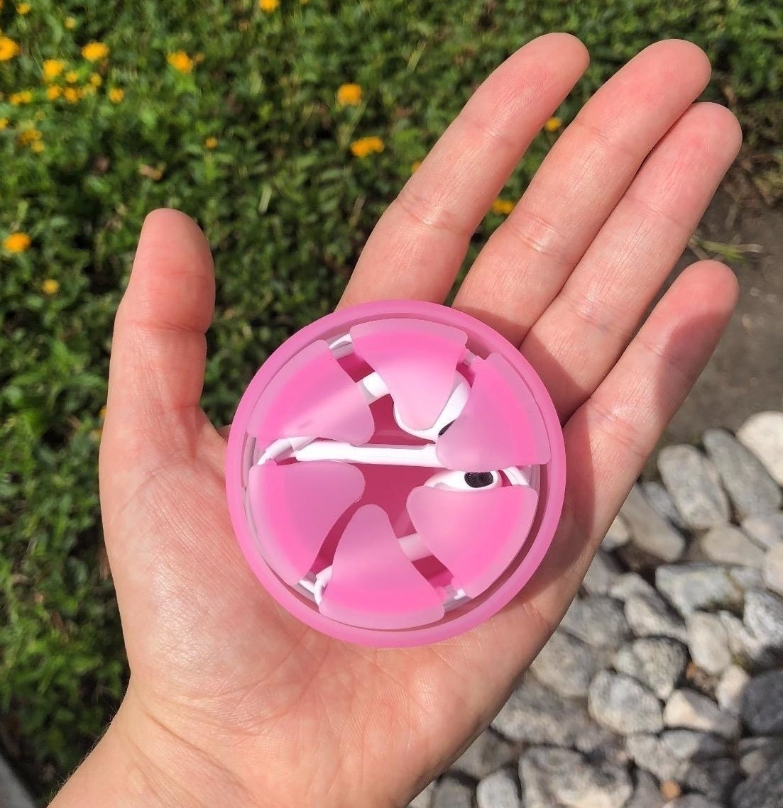 Reviewer holding the pink case in their palm with the earbuds wrapped inside